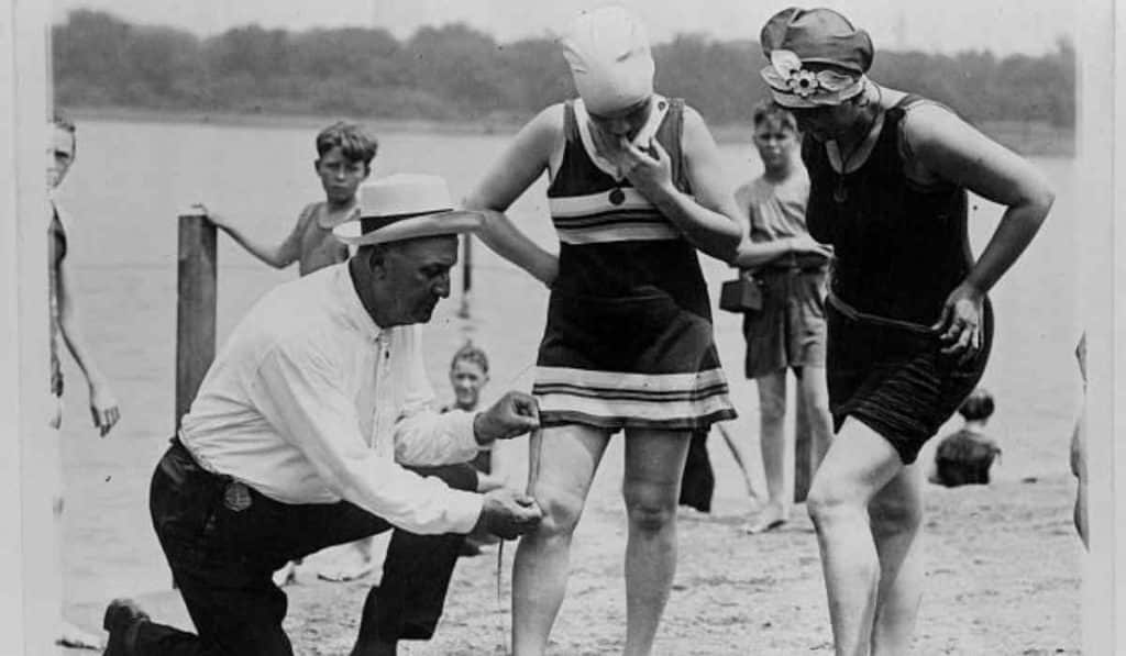 beach policeman measuring the distance between women’s knees and the bottom of swimsuits